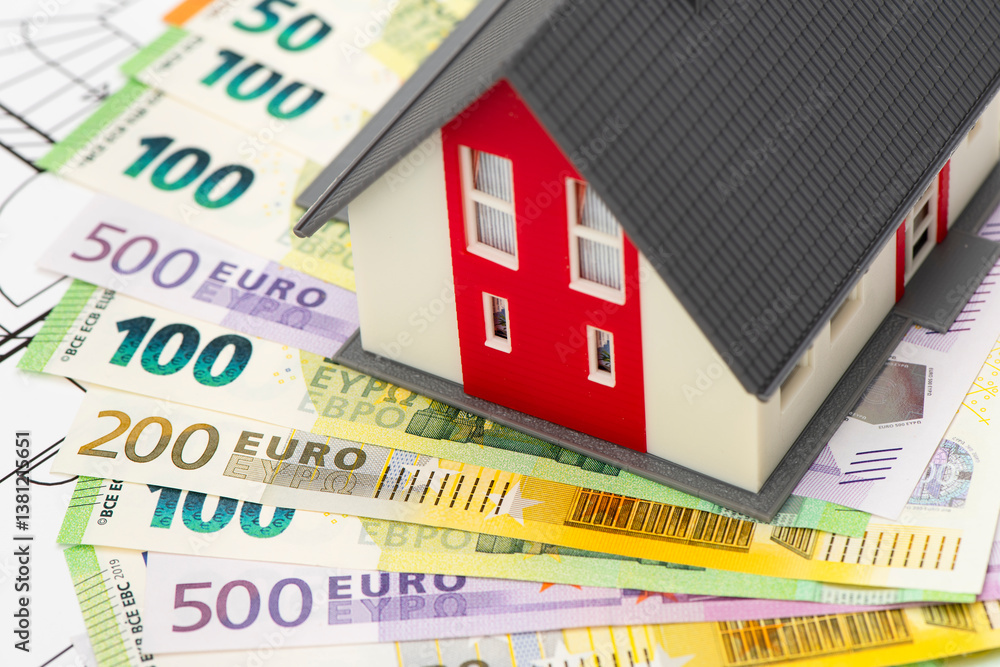 Ein Modellhaus steht auf vielen Euro Banknoten als Symbol für die Baufinanzierung