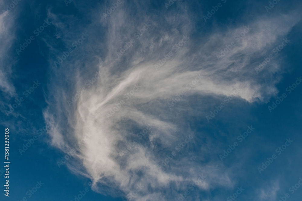 A delicate, feathery white cloud formation stretches across a vibrant blue sky, creating a soft, swirling pattern that evokes movement and tranquility. A delicate, feathery white cloud formation stretches across a vibrant blue sky, creating a soft, swirling pattern that evokes movement and tranquility.