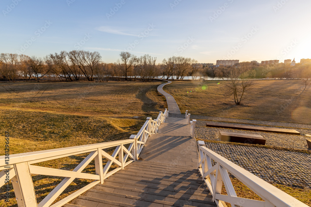 Fototapeta premium A long white wooden staircase leads up to a grassy hill