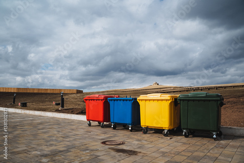 A vibrant and visually appealing row of colorful trash cans lines the busy sidewalk, creating an eyecatching and lively scene that attracts many pedestrians and curious passersby alike