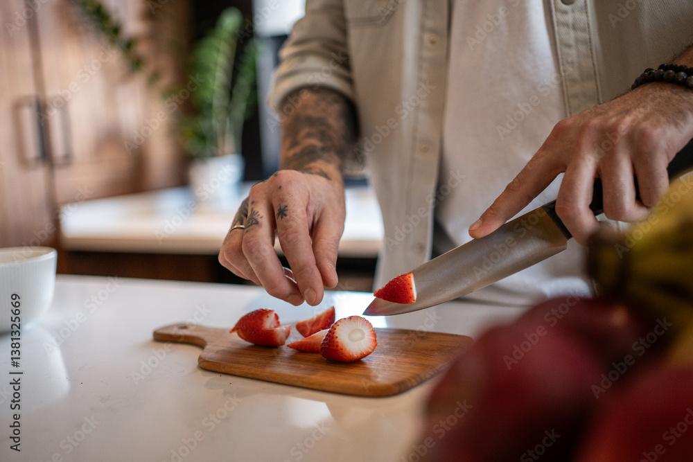 Obraz premium Chef slicing strawberries on wooden cutting board in modern kitchen