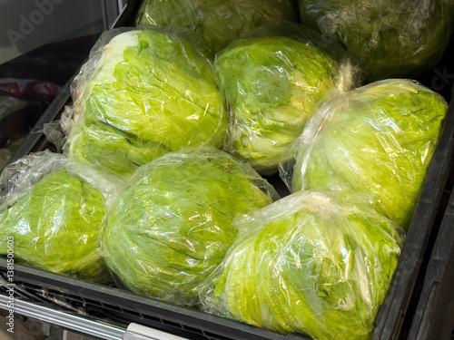 Fresh iceberg lettuce heads wrapped in plastic at grocery store display