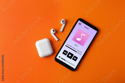 Φωτογραφία Mobile phone with open music player app, earphones and case on dark orange backg
