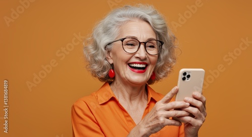 Wallpaper Mural A smiling elderly woman with curly gray hair holds her smartphone, enjoying a moment of laughter. She wears stylish glasses and bold red earrings, set against a vibrant orange background. Torontodigital.ca