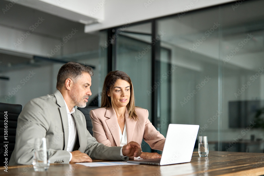 Smiling professional business woman manager consulting older Indian man client or colleague looking at laptop computer technology discussing ebusiness project planning strategy at office meeting. Smiling professional business woman manager consulting older Indian man client or colleague looking at laptop computer technology discussing ebusiness project planning strategy at office meeting.