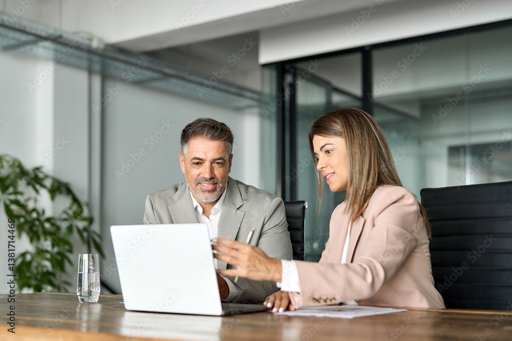 Obraz premium Two professional business executives working together at office meeting. Mature male manager consulting client or colleague looking at laptop discussing digital AI project planning corporate strategy.