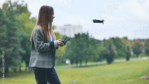 Billede på lærred Professional woman piloting drone near park pathway, blending work technology wi