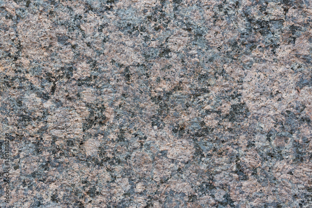 Granite texture. Natural gray granite with a grainy pattern. Stone background. Solid rough surface of rock. Durable construction and decoration material. Close-up.