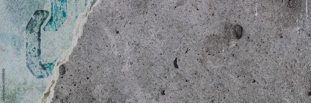 Torn old faded paper wallpaper with a retro pattern. Tattered scraps of paper on a concrete wall. Vintage texture for background and design. Closeup view with copy space.