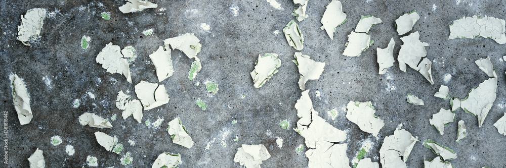 Peeling paint on the wall. Panorama of a concrete wall with old cracked flaking paint. Weathered rough painted surface with patterns of cracks and peeling. Panoramic texture for background and design.