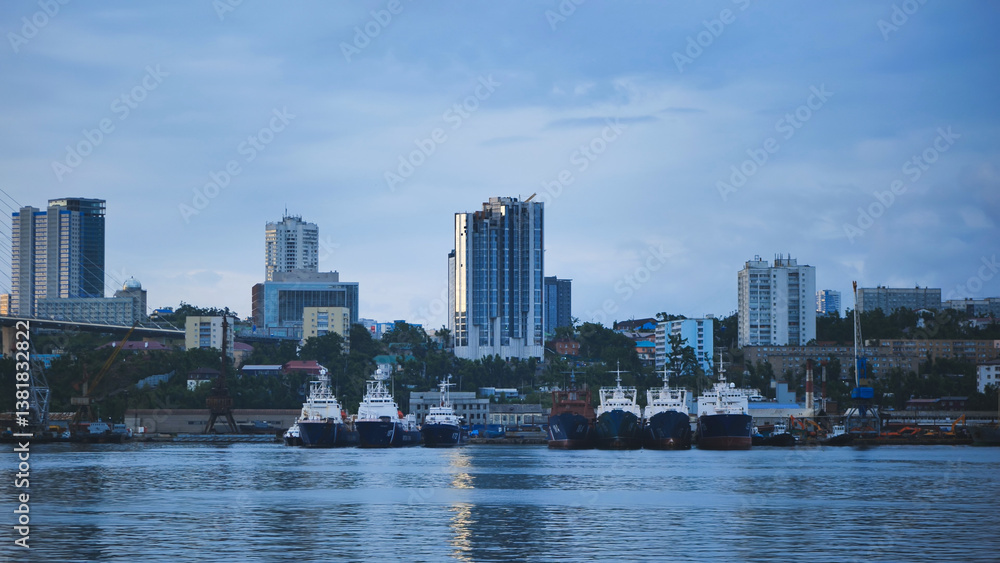 Fototapeta premium Cargo vessels docked at vladivostok seaport, golden bridge spanning cityscape under overcast sky