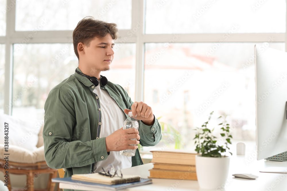 Male student with bottle of water studying online at home