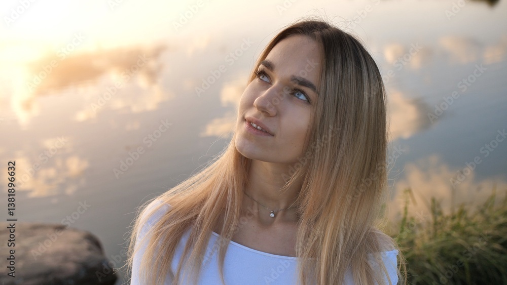 Blonde woman gazing at sunset clouds mirroring tranquil lake waters, capturing peaceful landscape's ethereal atmospheric glow Blonde woman gazing at sunset clouds mirroring tranquil lake waters, capturing peaceful landscape's ethereal atmospheric glow