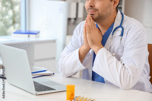 Male doctor praying at work...