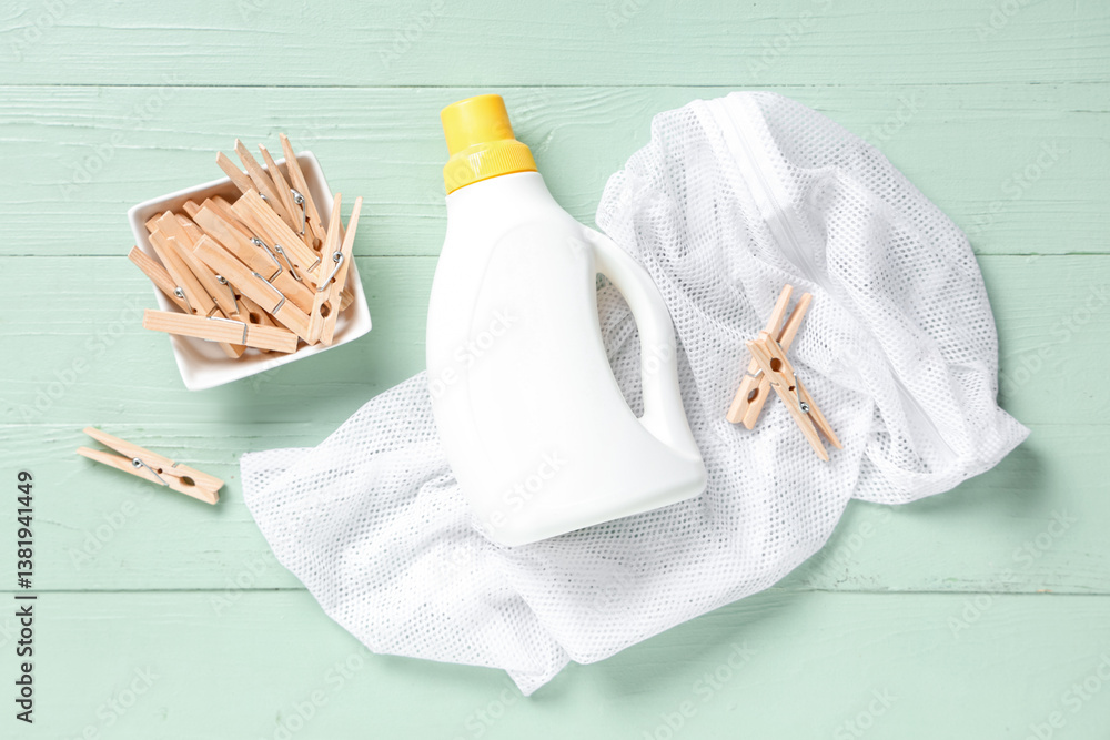 Bowl of clothespins with laundry detergent and string bag on green wooden background