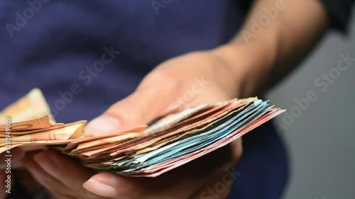 Close up of a mid adult woman checking her energy bills at home, sitting in her living room. She has a worried expression