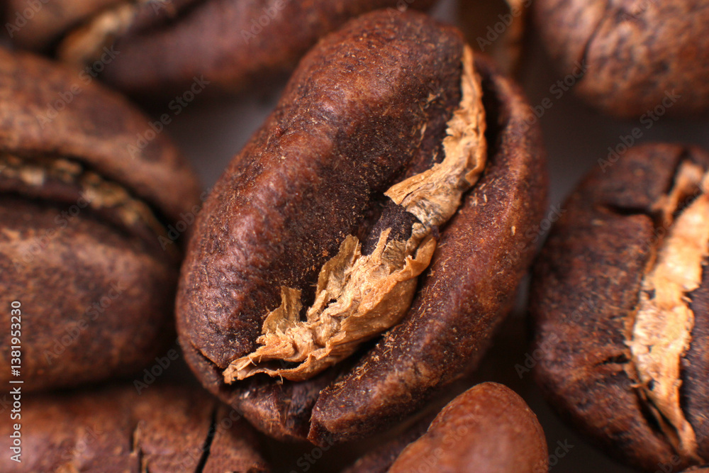 Fototapeta premium Close-up of a single roasted coffee bean, split open, revealing its inner texture amidst a pile of beans. Perfect for food photography or coffee blogs.