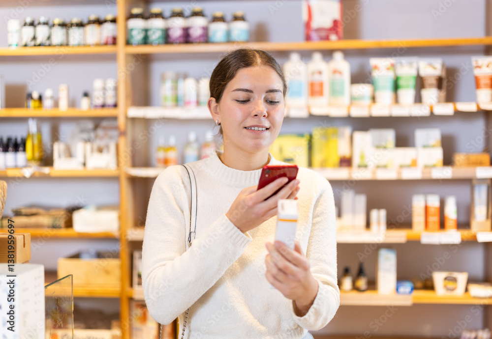 Young woman scans the barcode of a package of food supplements in an eco supermarket. European woman uses a QR code to read detailed instructions and information on how to use the dietary supplement Young woman scans the barcode of a package of food supplements in an eco supermarket. European woman uses a QR code to read detailed instructions and information on how to use the dietary supplement