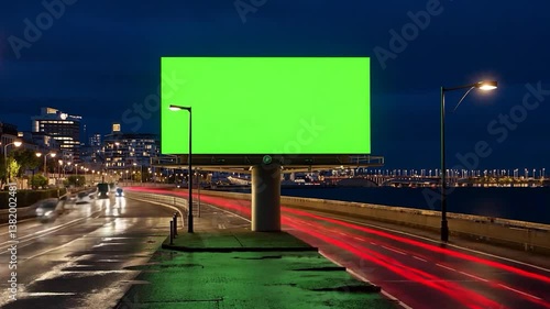 Large blank green screen billboard on a city street at night, perfect for advertising campaigns, urban marketing