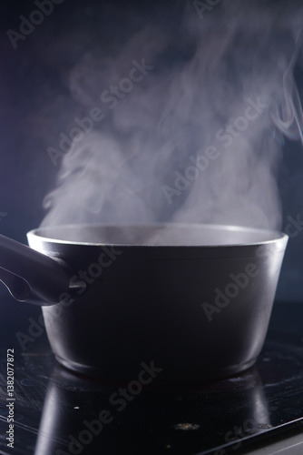 фотографія Cooking pot emits steam on a dark kitchen surface at night