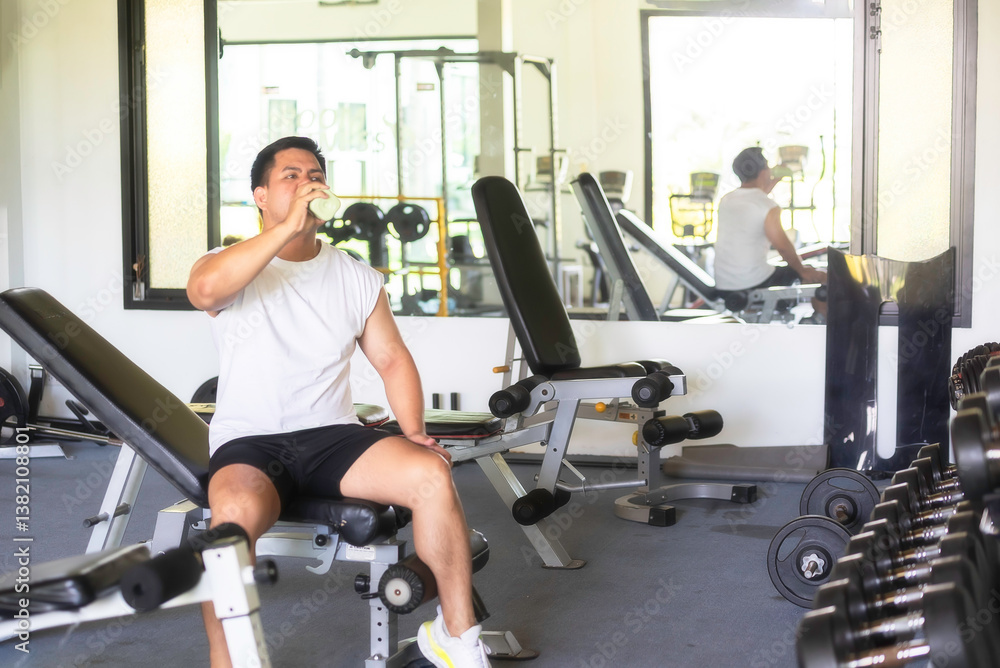 Man drinking water after training in gym. Healthy Concept Man drinking water after training in gym. Healthy Concept