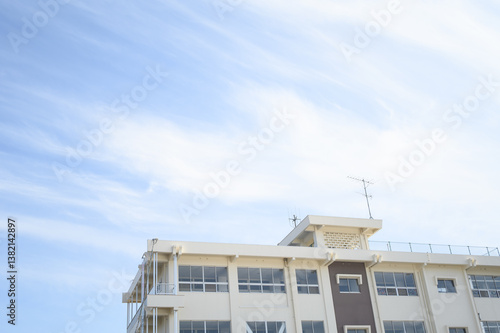 青空の下に建つ学校の校舎と屋上のアンテナ