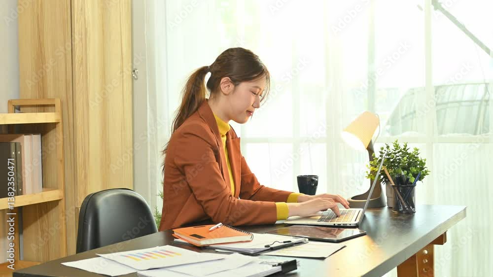 Smiling young business working at a home office desk with laptop and documents Smiling young business working at a home office desk with laptop and documents