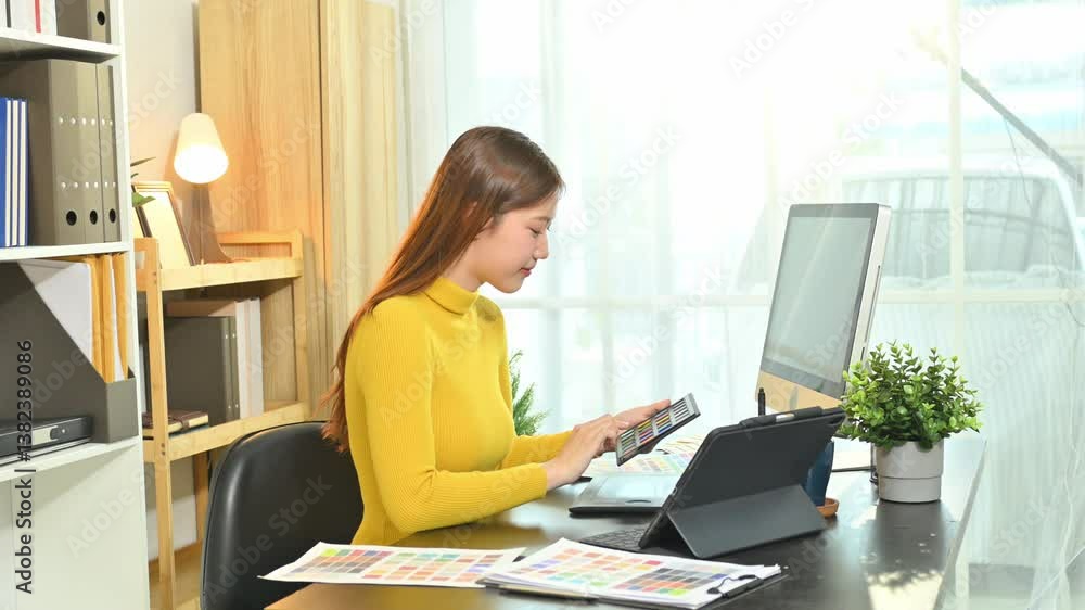Smiling young designer working on digital tablet and color samples at home office Smiling young designer working on digital tablet and color samples at home office