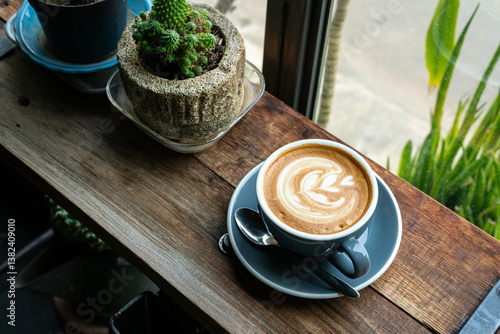 Obraz na płótnie Hot coffee latte with latte art milk foam in cup mug on wood desk on top view. As breakfast In a coffee shop at the cafe,during business work concept,vintage style w salonie