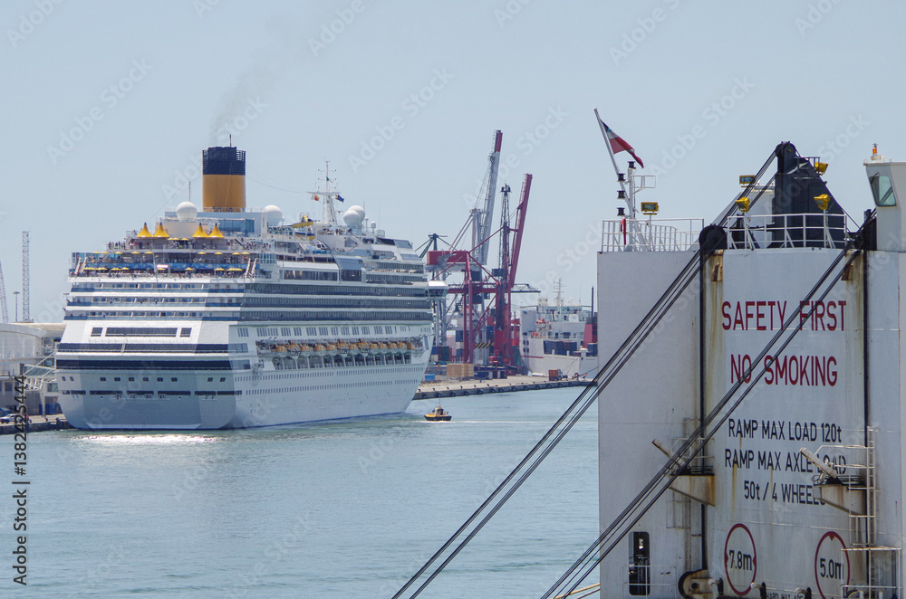 Modern family cruiseship Favolosa sail away departure with other cruise ship liners in port of Barcelona, Spain on sunny summer day seen from landside during Mediterranean cruising