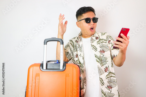 Worried young traveler tourist Asian man 20 years old wears casual clothes hat with backpack holding suitcase and mobile phone
