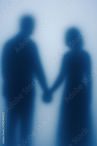 Couple holding hands with blurred outlines in a soft light setting