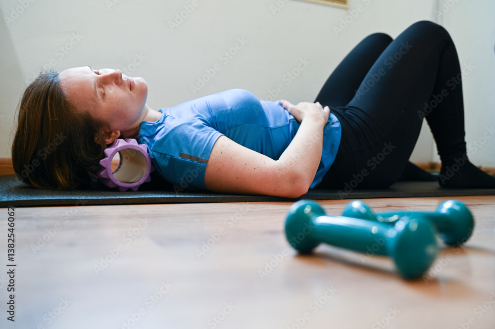 Woman doing exercises lying on roller at home. Strengthens muscles. Girl doing gymnastics with roller and dumbbells
Woman doing exercises lying on roller at home. Strengthens muscles. Girl doing gymnastics with roller and dumbbells