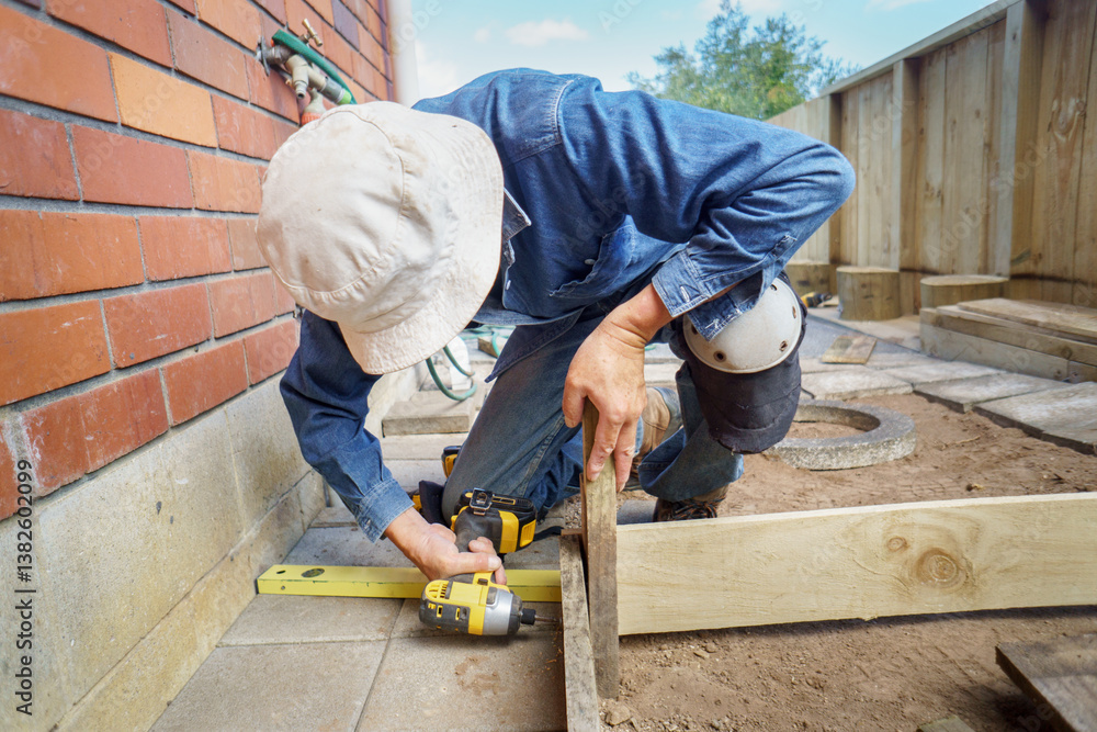 Man building a raised vegetable garden using a cordless screwdriver.