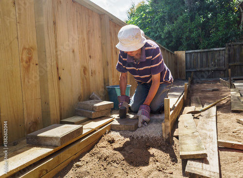Obraz na płótnie Man laying brick pavers in the backyard garden. w salonie