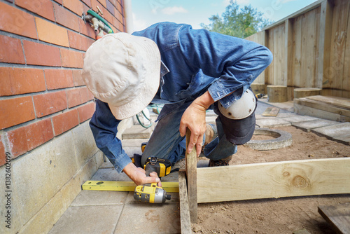 Man building a raised vegetable garden using a cordless screwdriver.