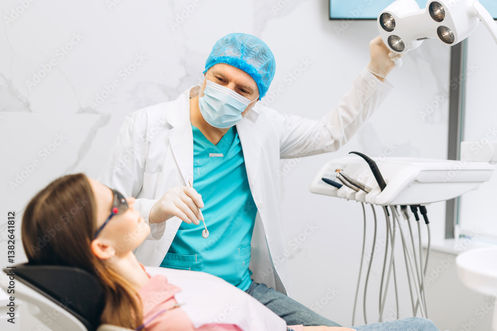 Obraz premium Male stomatologist in uniform taking visional inspection of woman on the chair in dental clinic