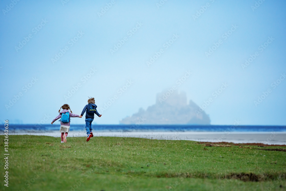 Children travelers run, head to distant foggy Mont Saint Michel