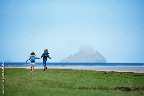 Obraz na płótnie Children travelers run, head to distant foggy Mont Saint Michel w salonie