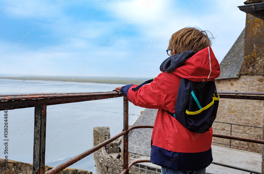 Child boy enjoying seaside view from a Mont Saint Michel wall