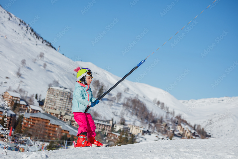 Cute skier girl on tow lift enjoy snowy landscape in bright gear