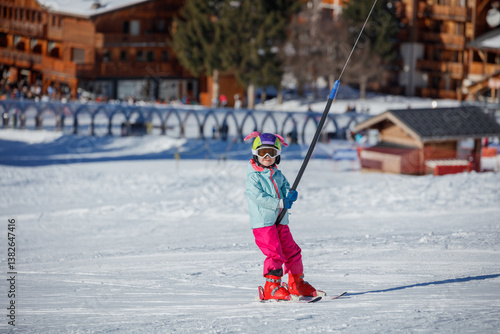 Obraz na płótnie Child girl in pink pants riding on ski lift at mountain resort w salonie