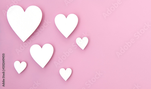 Photos Wooden hearts on a baby pink bacground with coy space.