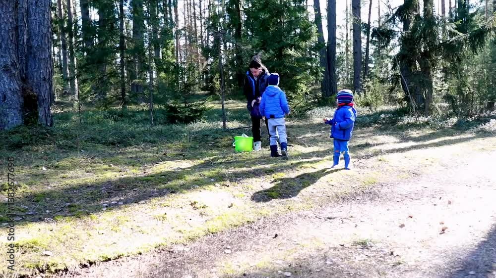 Children explore nature in a forest during a sunny winter day while an adult supervises playtime Children explore nature in a forest during a sunny winter day while an adult supervises playtime