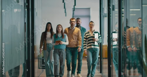 Business team in a modern open space startup office walking together. Diverse group of businesspeople smiling while having a discussion. Successful mixed race colleagues collaborating on a new project