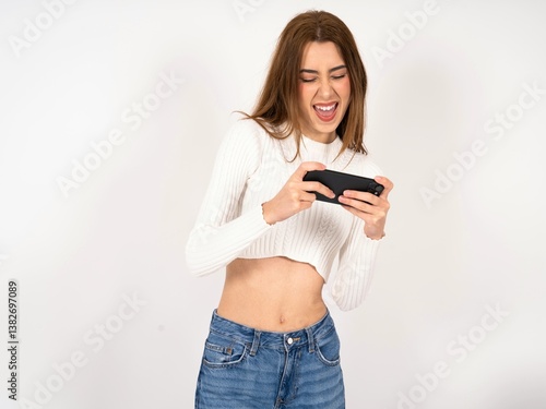Caucasian young girl wearing white T-shirt holding in hands cell playing video games or chatting