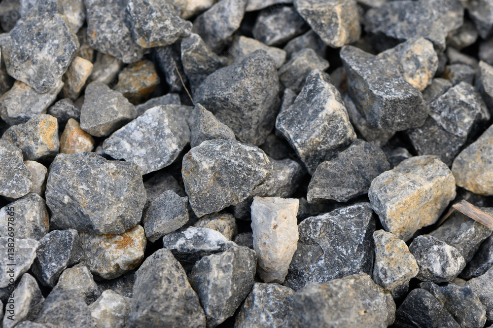 Natural gray gravel aggregate creates a sturdy foundation for landscaping and construction in a sunny outdoor setting Natural gray gravel aggregate creates a sturdy foundation for landscaping and construction in a sunny outdoor setting