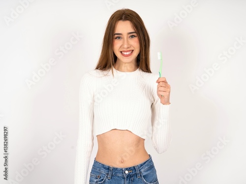 Caucasian young girl wearing white T-shirt holding a toothbrush and smiling. Dental healthcare concept.