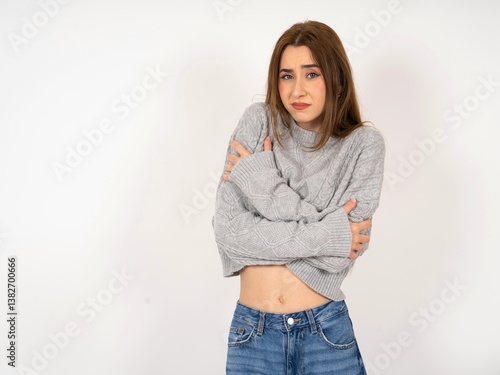Caucasian young girl wearing grey sweater shaking and freezing for winter cold with sad and shock expression on face.