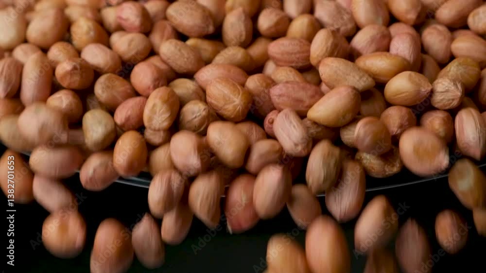 Raw whole dried peanut kernels pour, close-up, slow motion Raw whole dried peanut kernels pour, close-up, slow motion